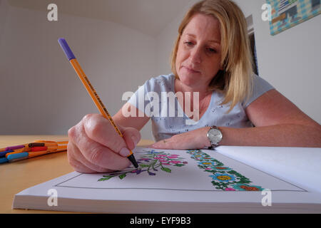 An adult woman colouring in a vintage design colouring in book, a new trend in relaxation for adults Stock Photo