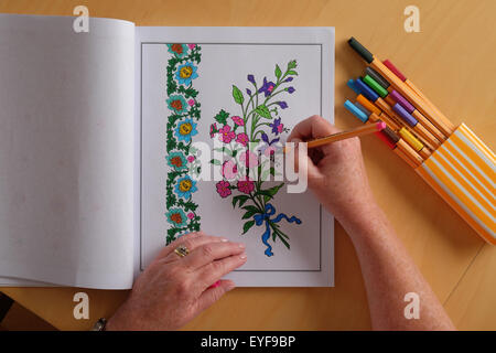 An adult woman colouring in a vintage design colouring in book, a new trend in relaxation for adults Stock Photo