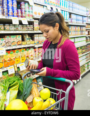 Woman in supermarket using smart phone Stock Photo