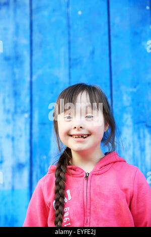 Young girl smiling on background of the blue wall Stock Photo