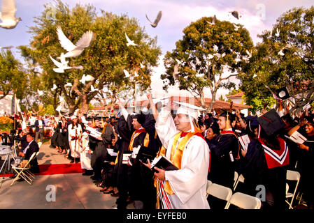 Happy community college graduates wave as doves are released at commencement ceremonies in Long Beach, CA. Stock Photo