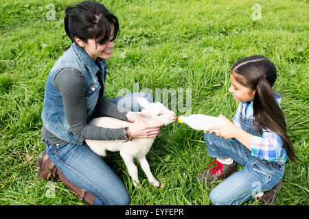Mother with daughter (6-7) feeding lamb Stock Photo