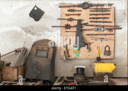 old workbench with old work tools hanging on wall garage Stock Photo