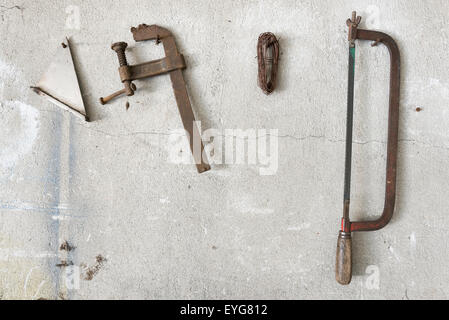 old hacksaw and clamp  hanging on garage wall Stock Photo