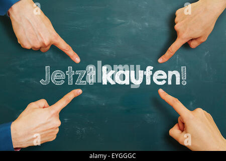 hands pointing to German slogan 'Jetzt kaufen!' (buy now!) on a chalkboard Stock Photo