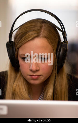 Secondary school pupil wearing headphones and using IT during a music lesson, Surrey, UK. Stock Photo
