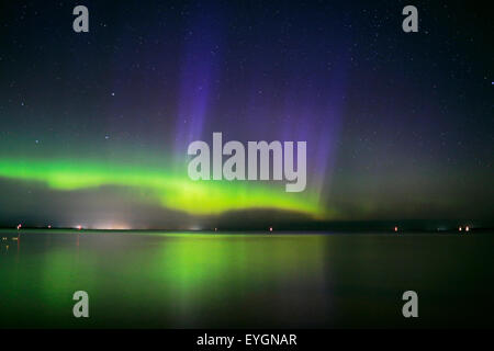 Green yellow Aurora borealis with purple light pillars flickering brilliantly over Lake Simcoe Stock Photo