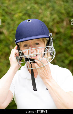 Portrait of an elderly woman cricketer wearing a batswoman's safety helmet Stock Photo