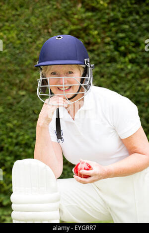 Portrait of an elderly woman cricketer wearing a batswomans' safety helmet with face guard Stock Photo