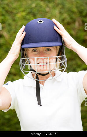 Portrait of an elderly woman cricketer wearing a batswoman's safety helmet Stock Photo