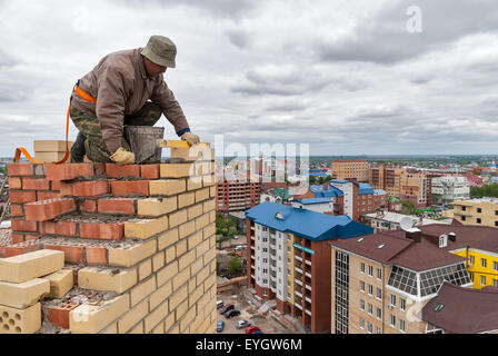 Bricklayer works on high house construction Stock Photo