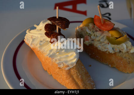 Pinchos Españoles at Lizarran, Spain.  In the foreground is cream cheese, raisin & a date, b/g ensalada russa, olive & tomato Stock Photo