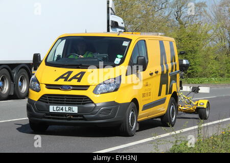 A 2014 AA BREAKDOWN RESCUE YELLOW VAN DRIVING ALONG A MAIN A ROAD WITH A TRAILER CARRYING A MOTORCYCLE Stock Photo