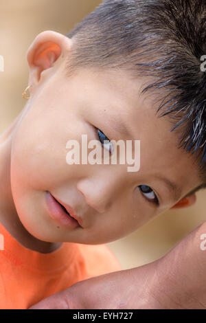 Portrait of a little mongoloid boy happy and innocent with copy space, curious look in the eyes Stock Photo