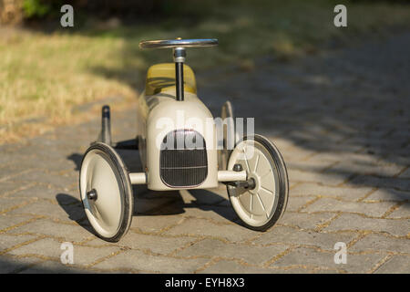 old metal pedal car for children from the 19 th century on the garden, front view Stock Photo