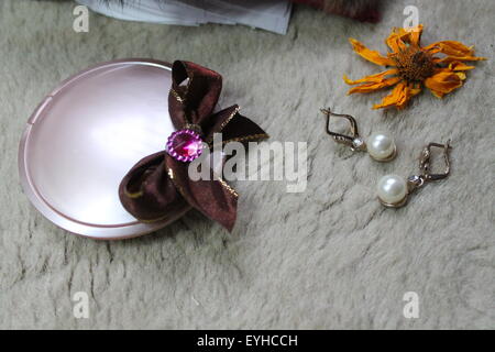 nacre circle powder, bow, earrings with pearls, orange dry flowers Stock Photo