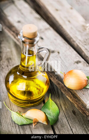 Decanter sunflower oil with onion slices on wooden table Stock Photo