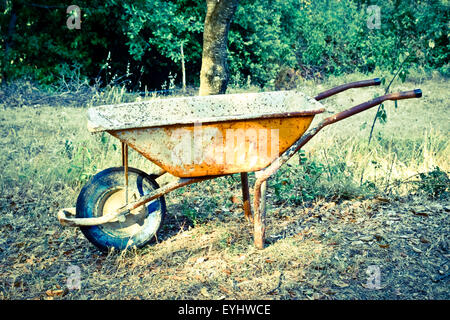 Empty old wheelbarrow in a garden. Stock Photo