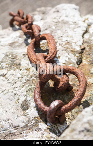 looking down at chain links hanging over rock Stock Photo