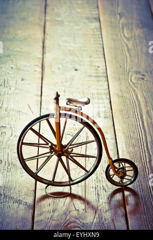 Old bicycle with big and small wheel on a wooden surface. Stock Photo