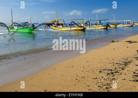 Local boats, called jukungs, lined up at anchor on a beach in Sanur, SE Bali, Indonesia Stock Photo