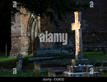 Cross headstone lit up by the evening sunlight. Banbury, Oxfordshire, England Stock Photo