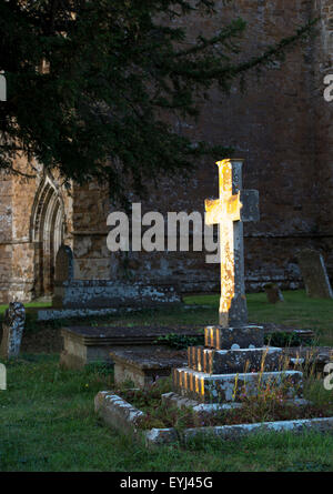 Cross headstone lit up by the evening sunlight. Banbury, Oxfordshire, England Stock Photo