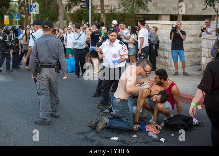 Jerusalem. 30th July, 2015. People offer first aid to a young Israeli in a stabbing attack during the annual gay pride parade in Jerusalem, . Six people were stabbed at Jerusalem's annual gay pride parade on Thursday, in one of the gravest attacks on the gay community in Israel, Israeli officials and eyewitnesses told Xinhua. A police spokesperson said the assailant was captured and identified as Yishai Schlissel, a Jewish ultra-Orthodox man who carried out a similar attack in 2005, injuring three people. Credit:  Xinhua/Alamy Live News Stock Photo