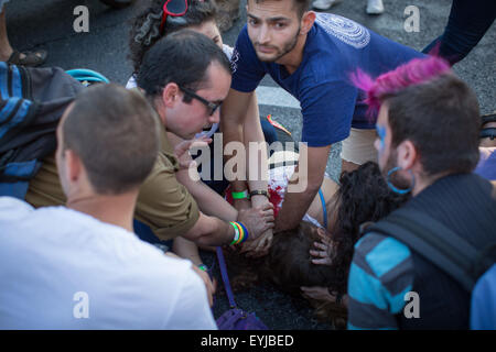 Jerusalem. 30th July, 2015. People help a young Israeli to stanch the wound in a stabbing attack during the annual gay pride parade in Jerusalem, . Six people were stabbed at Jerusalem's annual gay pride parade on Thursday, in one of the gravest attacks on the gay community in Israel, Israeli officials and eyewitnesses told Xinhua. A police spokesperson said the assailant was captured and identified as Yishai Schlissel, a Jewish ultra-Orthodox man who carried out a similar attack in 2005, injuring three people. Credit:  Xinhua/Alamy Live News Stock Photo