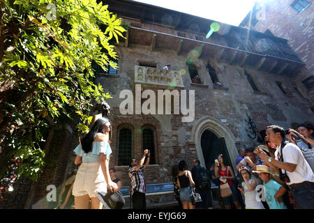 Verona. 27th July, 2015. A woman poses with the statue of Juliet, while other tourists take photos of the Balcony of Juliet's House in Verona July 27, 2015. Verona is a city in north Italy's Veneto. As one of the main tourist destinations in north Italy, the city has artistic heritages, annual fairs, shows, and operas. It was listed as a UNESCO world heritage site in 2000 for its historical buildings. © Jin Yu/Xinhua/Alamy Live News Stock Photo