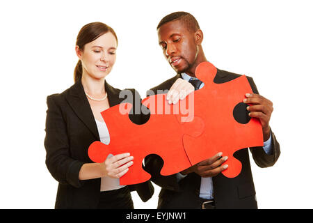 Man and woman connecting two big oversized red jigsaw puzzle pieces Stock Photo