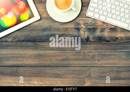 Digital tablet pc, keyboard and red cup of coffee on wooden table. Vintage style toned picture with light leaks Stock Photo