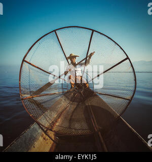 Myanmar travel attraction - Traditional Burmese fisherman with fishing net at Inle lake in Myanmar, view from boat. Vintage filt Stock Photo