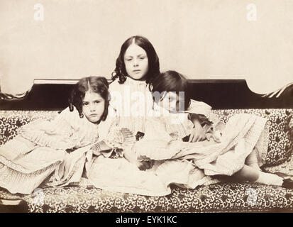 Alice Liddell (1852-1934) (right) with her sisters Edith (left) and Lorina (center) on a chaises longue. Alice Liddell is the namesake and inspiration behind Alice in Wonderland. Photographed by Charles Lutwidge Dodgson (1832-1898) better known as Lewis Carroll in 1858. Lewis Carroll made up some tales of Alice and her adventures down the rabbit hole to entertain them on a boating trip down the Isis in Oxfordshire in 1862.