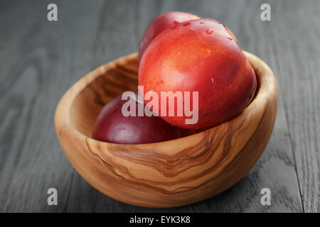 nectarines in olive wood bowl on oak table Stock Photo