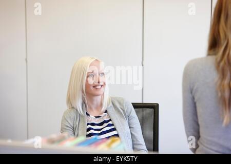 Two businesswomen chatting at  desk in office Stock Photo