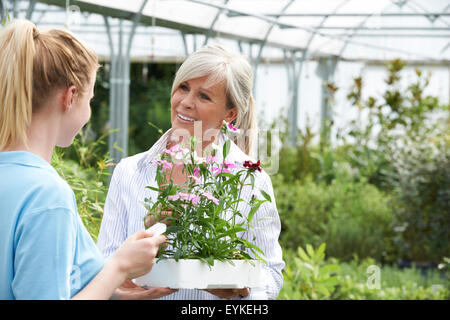 Staff Giving Plant Advice To Female Customer At Garden Center Stock Photo