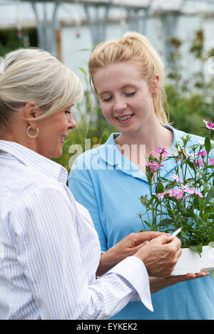 Staff Giving Plant Advice To Female Customer At Garden Center Stock Photo