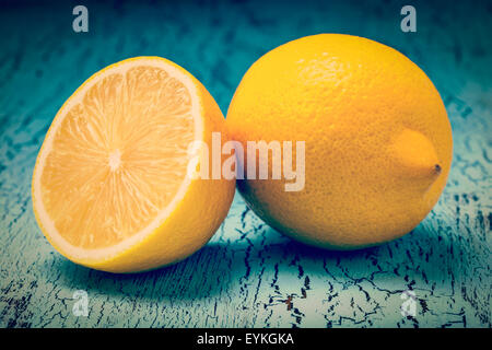Vintage retro effect filtered hipster style image of lemon and cut half slice on blue wooden background Stock Photo