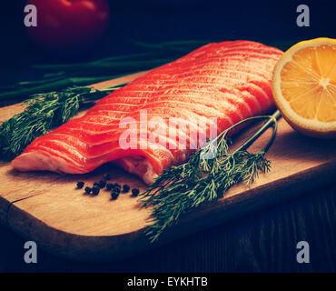 Vintage retro effect filtered hipster style image of fresh salmon piece on wooden cooking board with vegetables Stock Photo