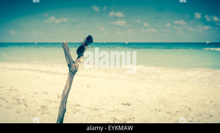 Sunglasses on wooden post on caribbean beach Stock Photo