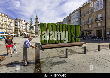 Local taking water with vegetable sculpture in grass of Vitoria Gasteiz in Plaza de la Virgen Blanca Stock Photo