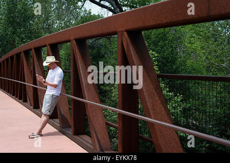 A man reading an iphone on the Oak Creek pedestrian bridge in Sedona Arizona Stock Photo