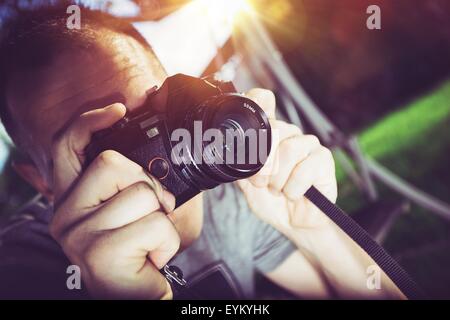 Retro Photographer. Caucasian Photographer with Vintage Analog Camera Taking Pictures. Stock Photo