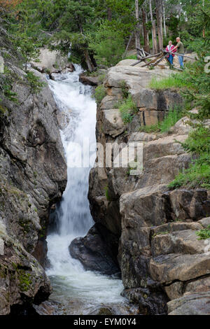 man woman couple viewing Chasm Falls waterfall on Old Fall River Road in Rocky Mountain National Park Colorado Stock Photo