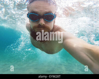 Young bearded man diving in a blue clean water Stock Photo