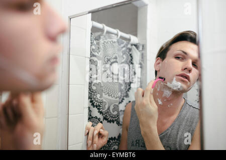 Male drag queen shaving before putting on make up and dressing up in preparation for a performance Stock Photo