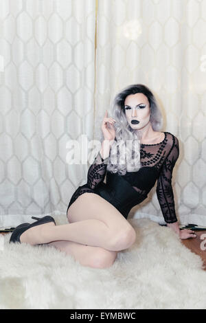 Male drag queen posing for pin-up style glamor portrait at home. Stock Photo
