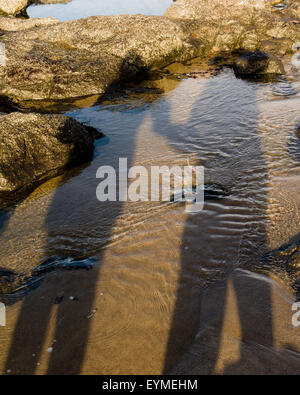 Shadows of a couple holding hands on a sandy beach Stock Photo