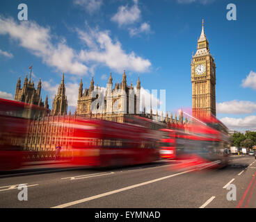 Big Ben in Westminster with red London Buses going past during the day. There is space for text in the image Stock Photo